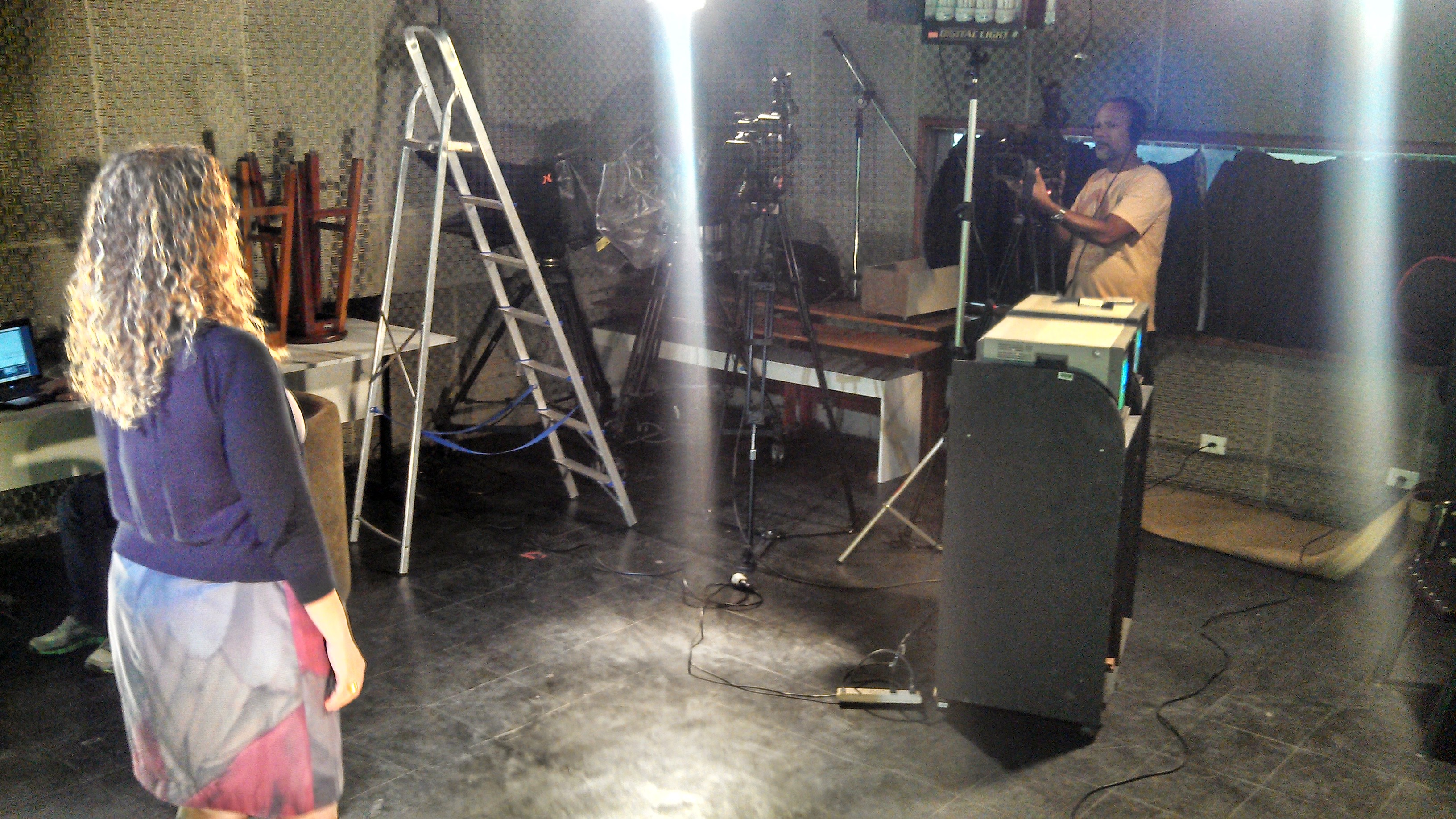 Apresentadora de TV sendo gravada por cinegrafista em um estúdio de TV.